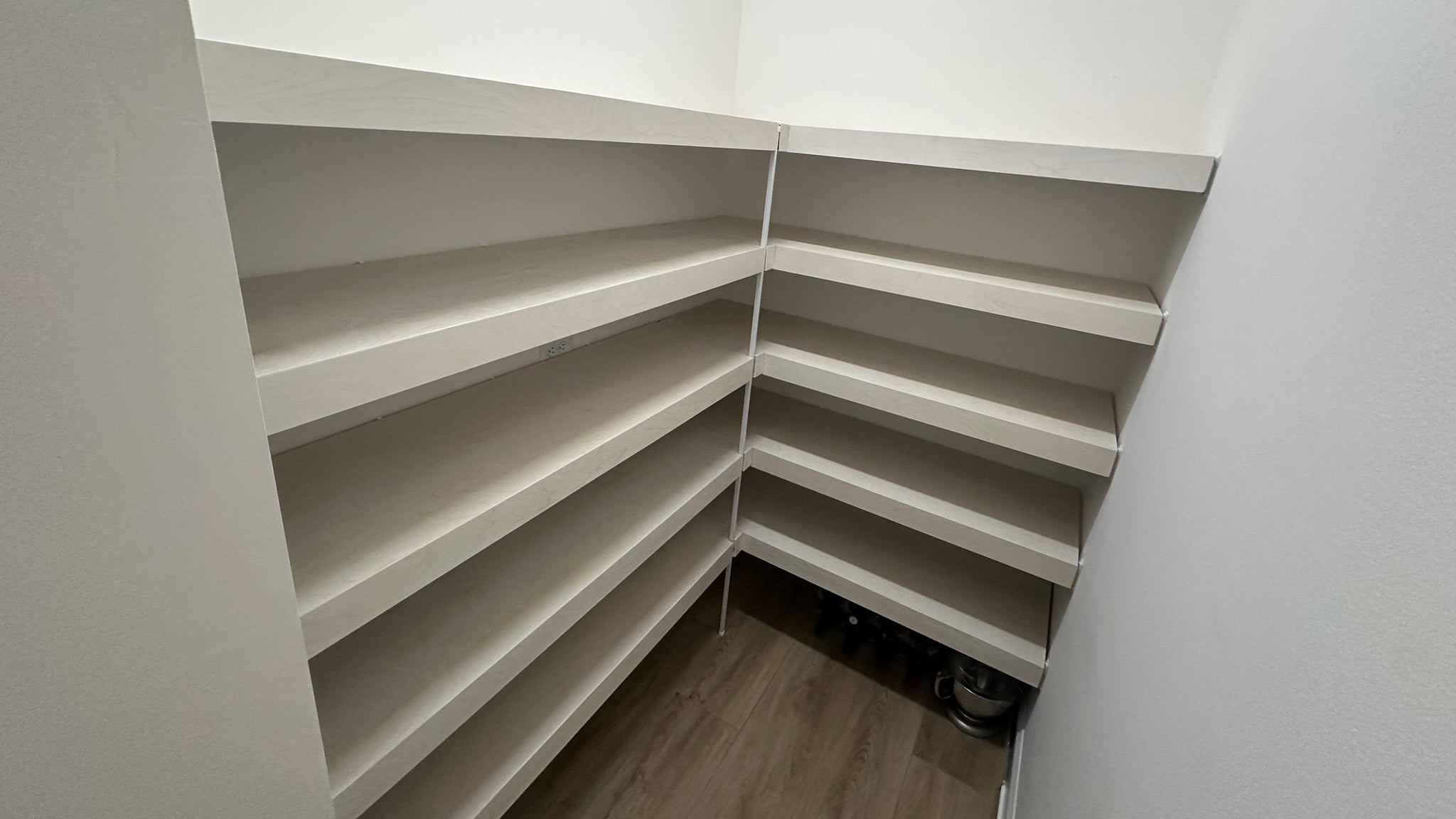 Corner pantry with white stained shelves in a minimalistic setting